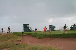 The volunteer crew rakes bunkers on Monday after the practice round.