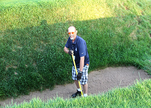 Dave Van Auken, superintendent at Bass Lake GC in Deerbrook, Wis., gives the Gremlin's Ear bunker a raking