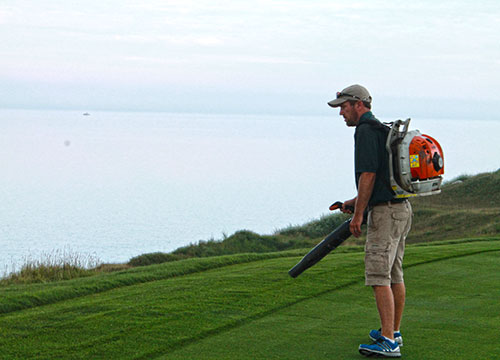 Several weather delays put some excess water on the turf. Crew members used blowers to remove some of it before mowing.