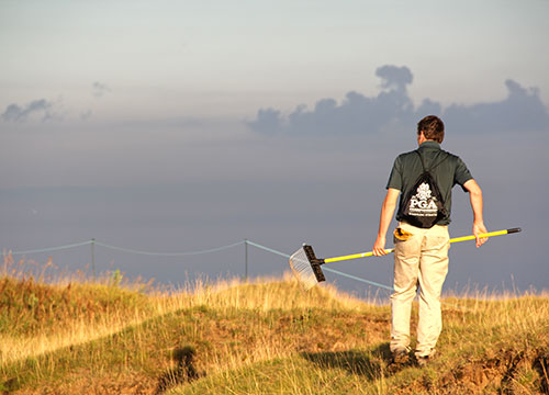 A bunker raker admires his work as the sun sets on the Straits Course.