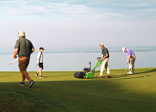 Golfer Steve Stricker mid-practice round encouraged the greens mowing crew to keep working while he putted out the hole.