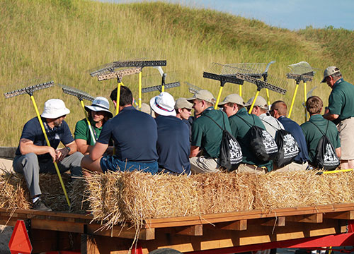 Volunteers with bunker rakes in hand ready for a hayride to the course for the first evening shift of maintenance.