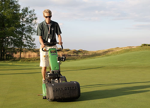 Walk mowing No. 5 green with a John Deere 180C. 