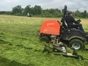 Reineking hops onto a mower himself to take down some of the fine fescue. 