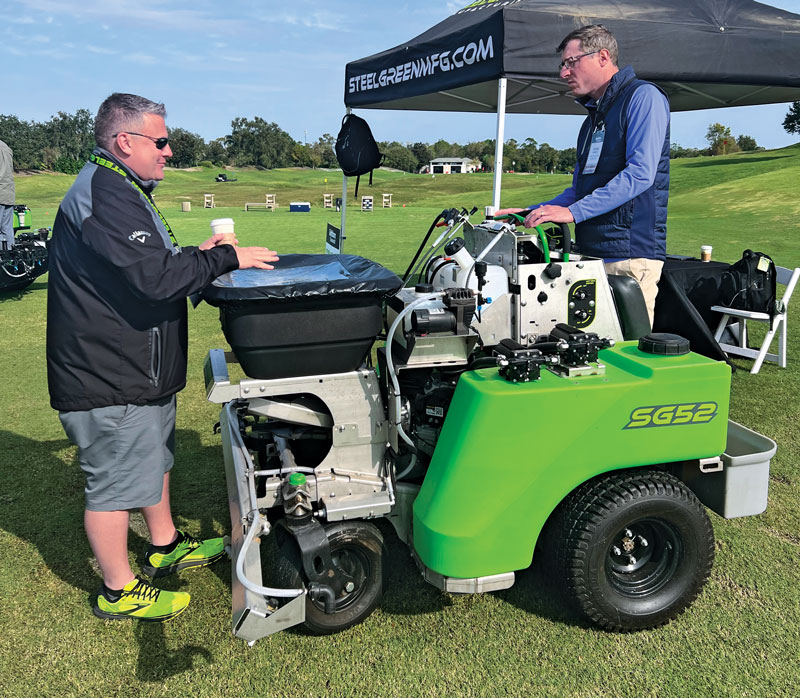 Matt Smith of Steel Green Manufacturing walks Ryan Emerich through the company’s SG52 zero-turn spreader-sprayer. (Photo: Golfdom Staff)