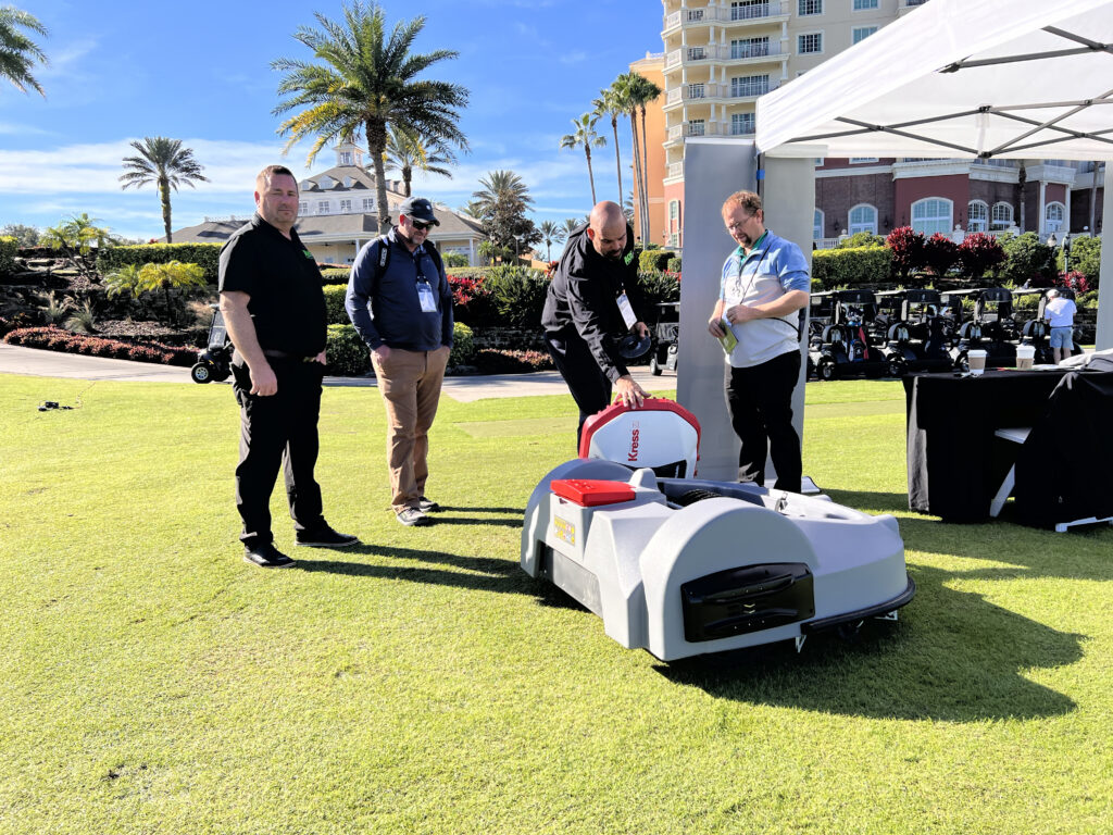 Joe Langton, president of Automated Outdoor Solutions (AOS), (with hand on the Kress mower) gives Anthony Williams (right), superintendent, Danville (Ky.) CC, a demonstration of the robotic mower.(Photo: Golfdom staff)