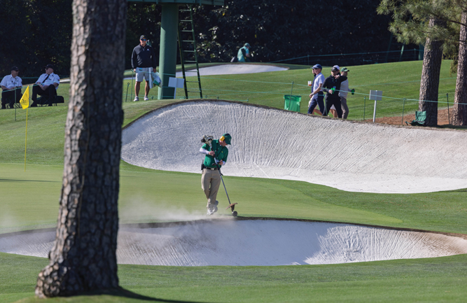 A Masters patron watches as a member of the grounds crew string-trims a bunker with precision. Owen worked every Masters from 1986 until last year, when he retired from the course and joined Turfgrass Inc. (Photo: Scott Ramsay)